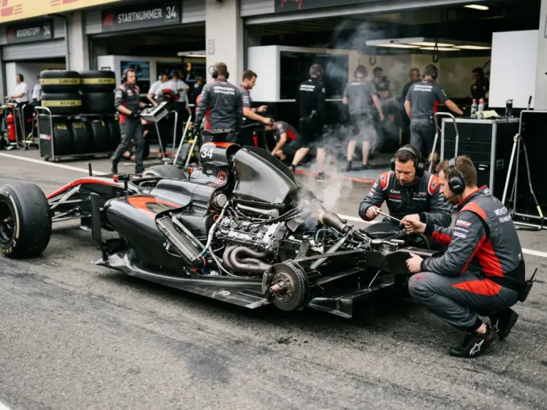 Formel-1-Fahrzeug mit geöffneter Motorhaube und Rauchentwicklung in der Boxengasse nach einem technischen Ausfall