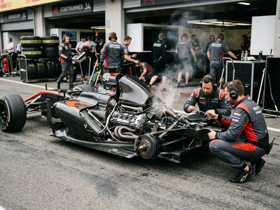 Formel-1-Fahrzeug mit geöffneter Motorhaube und Rauchentwicklung in der Boxengasse nach einem technischen Ausfall